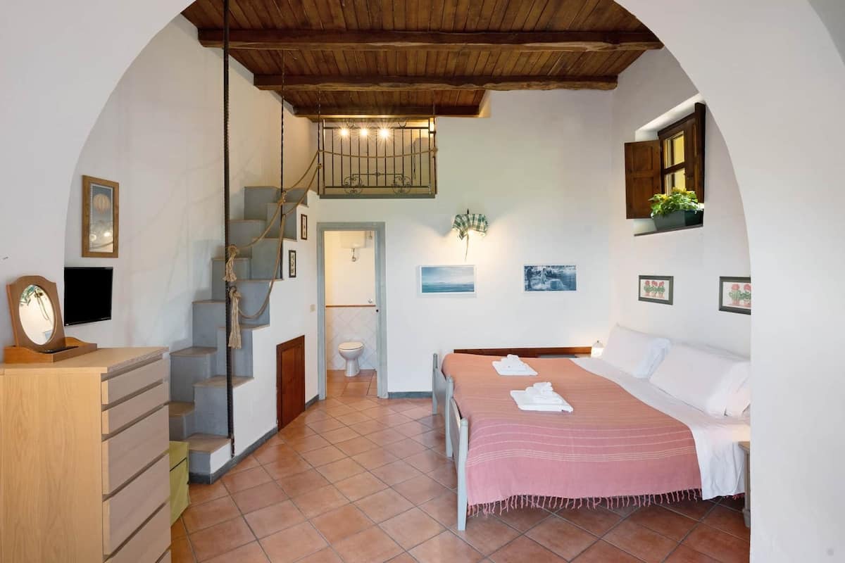 Ein Schlafzimmer mit Bett, Schreibtisch mit Spiegel, einer Treppe und einem Badezimmer.