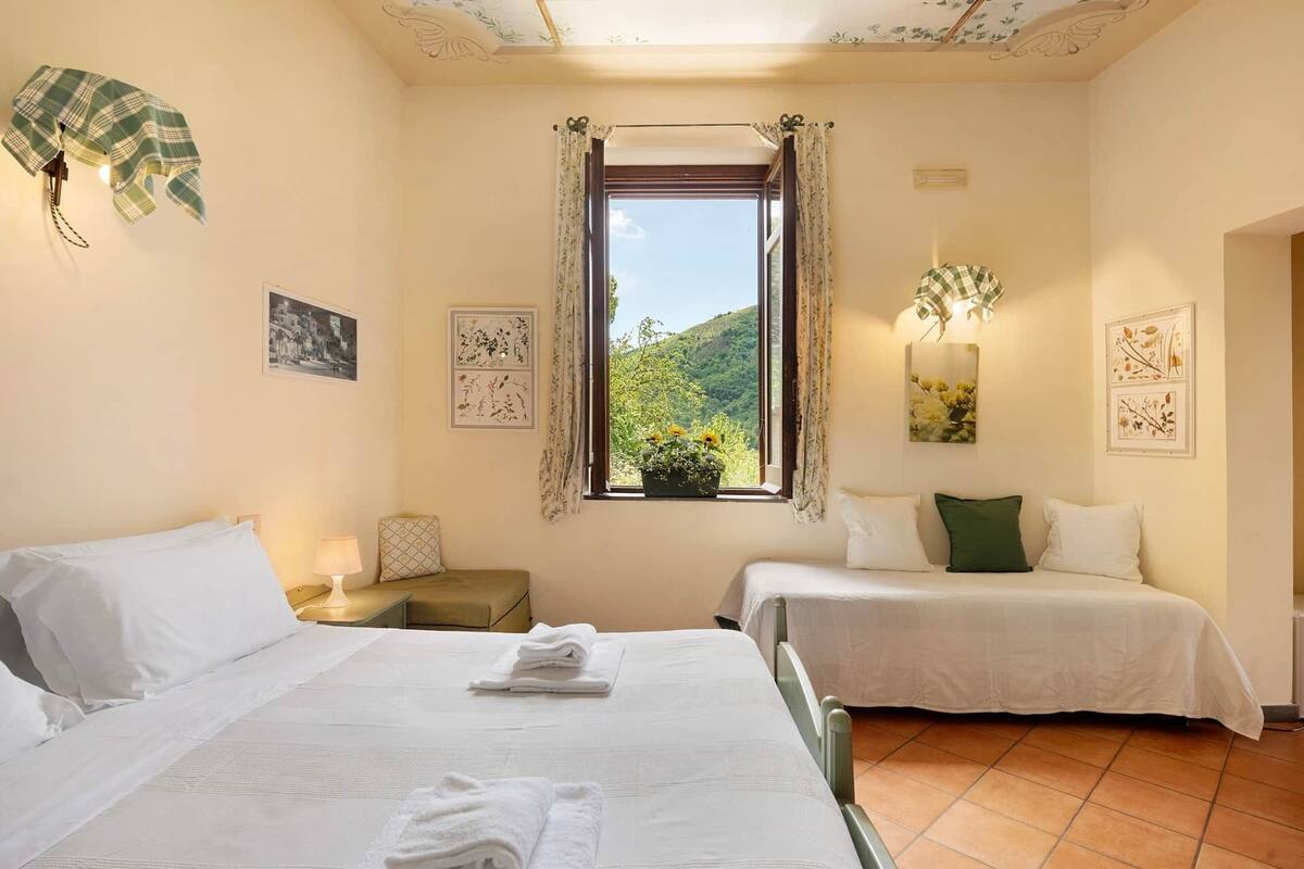 Ein Hotelzimmer mit zwei Betten, einem Fenster mit Blick auf Grünflächen und Wandbildern.