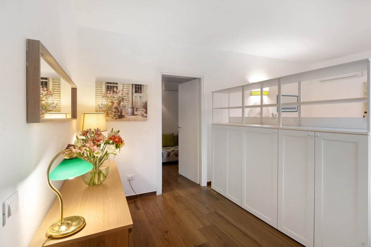 Ein Flur mit Holzboden, einem Schreibtisch mit Lampe, einem Spiegel und einem Wandbild.