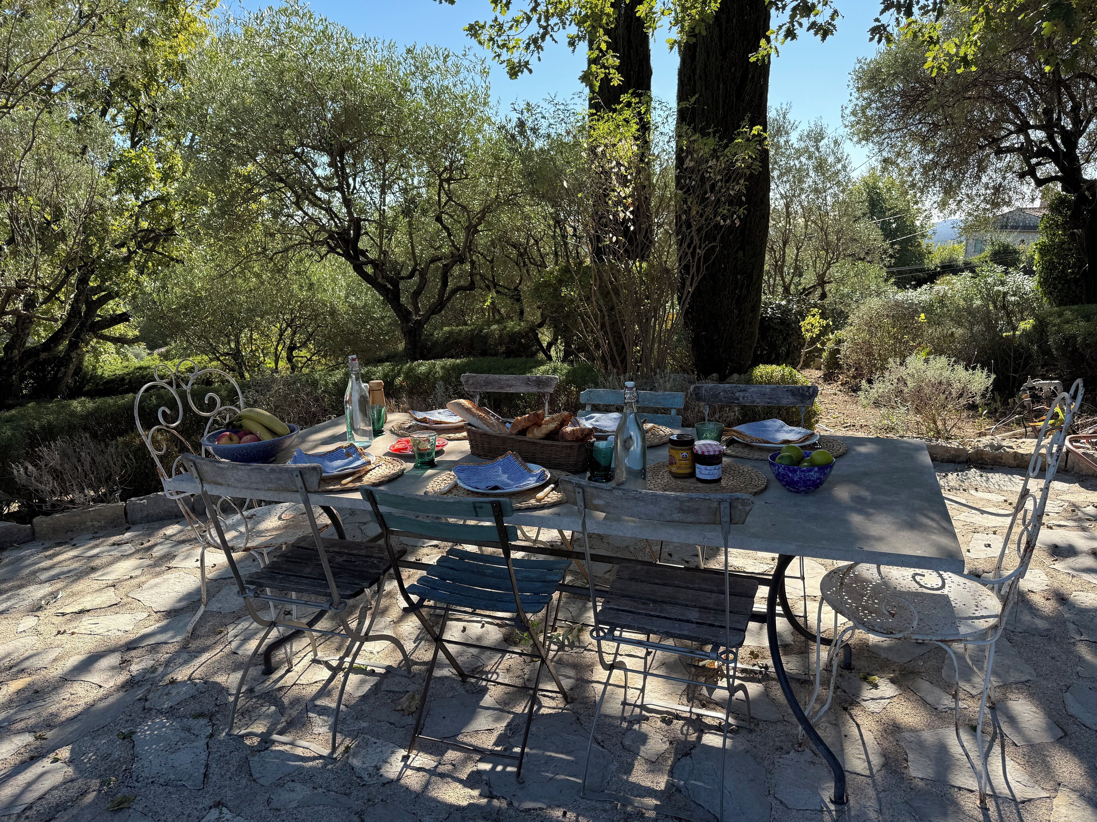 Un comedor al aire libre con una mesa dispuesta para dos personas, rodeado de árboles y vistas del paisaje.