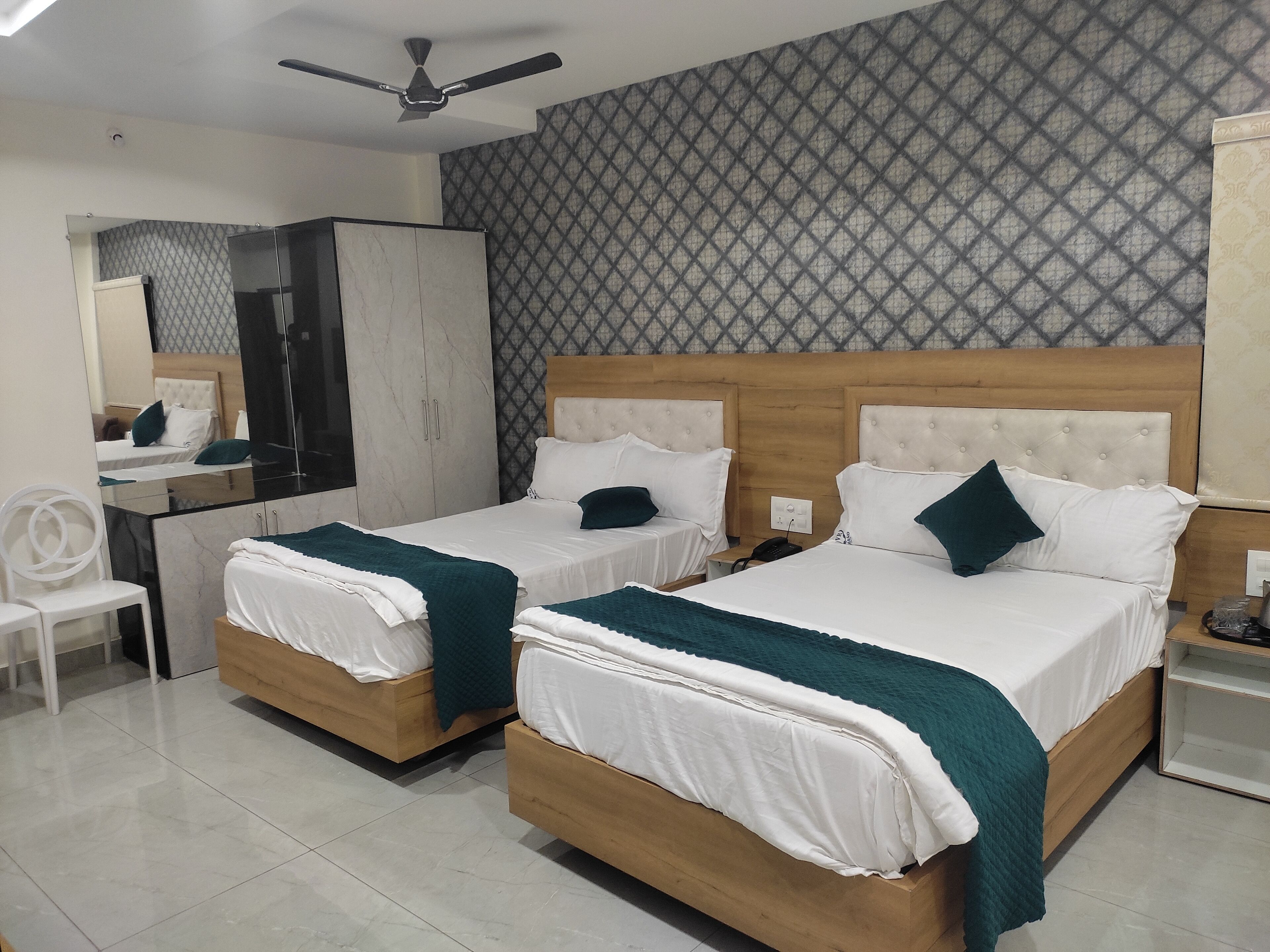 A hotel room with two beds, a wardrobe, a desk, and a mirror.