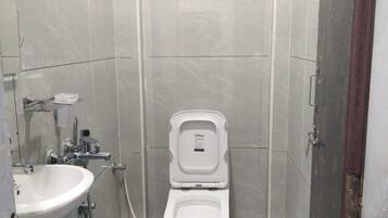 Un baño pequeño con azulejos, un inodoro, un lavamanos y un cubo.