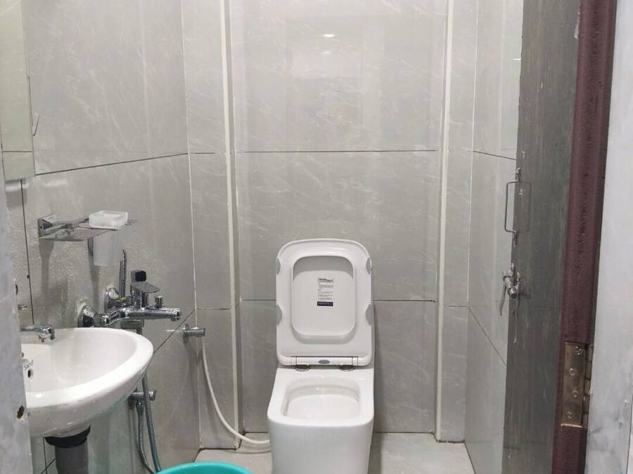 Un baño pequeño con azulejos, un inodoro, un lavamanos y un cubo.