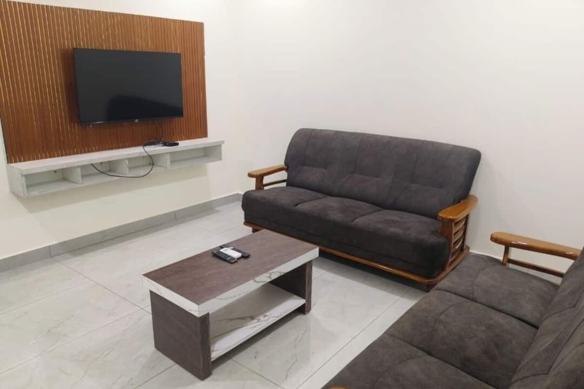 Una sala de estar con un sofá gris, una mesa de centro y un televisor montado en un panel de madera.
