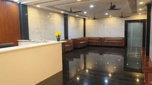 Egy modern előtér, amelyben recepció, ülősarok és mennyezeti ventilátorok találhatók.
