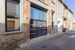 Un edificio con fachada de piedra, un gran portón de garaje y una ventana con persianas.