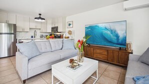 Ein modernes Wohnzimmer mit einem grauen Sofa, einem weißen Couchtisch und einem großen Flachbildfernseher.