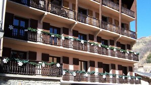 Ein mehrstöckiges Hotel mit Balkonen, die mit Grünpflanzen und weißen Blüten geschmückt sind.