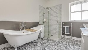 Ein Badezimmer mit freistehender Badewanne, einer gläsernen Dusche und Fliesen mit Muster.