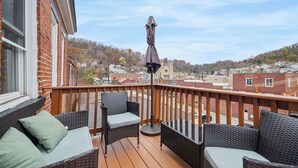 Un balcon agrémenté de meubles en osier, d’une table et d’un parasol.