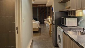 Habitación de hotel compacta con kitchenette, una cama, lavadora y un pequeño comedor.