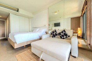 A modern bedroom with a bed, a sofa, a large mirror, and a television. - Zire Wongamat | Beachfront Seaview with Bathtub (Pattaya)