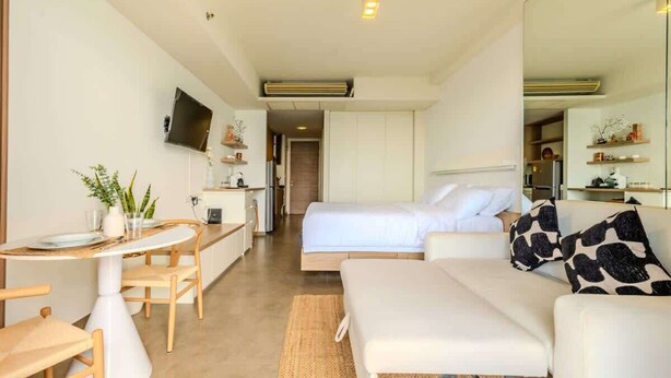 Una habitación de hotel moderna con cama, sofá, mesa de comedor y kitchenette.