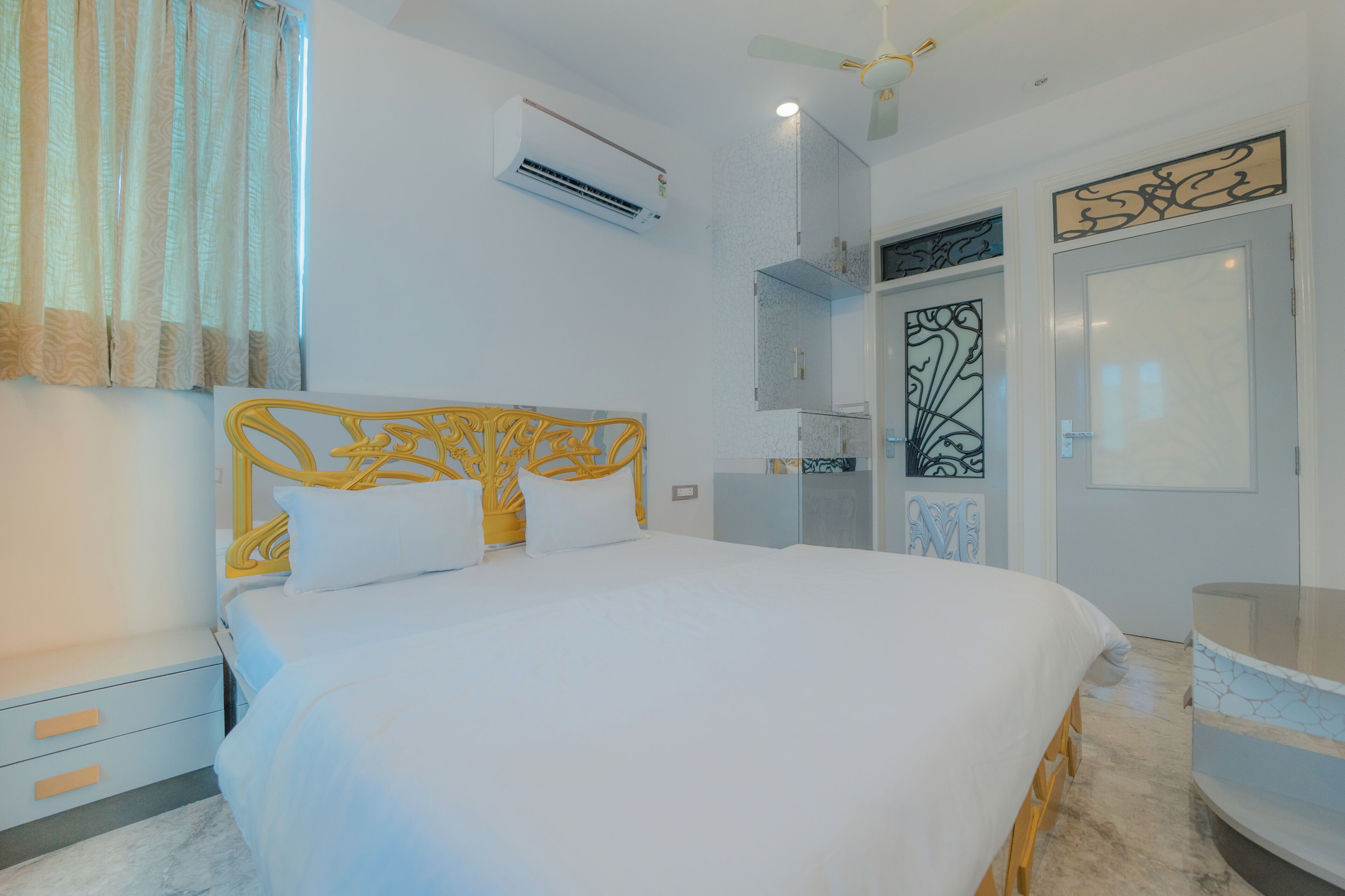 A bedroom with a bed, a nightstand, an air conditioning unit, a ceiling fan, and a bathroom with a shower and a toilet.