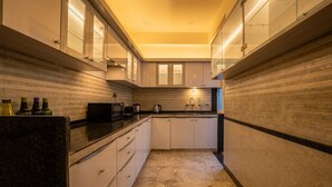 A narrow kitchen with white cabinets, a black countertop, and a tiled backsplash. - The Collectors Loft-A Luxury Private Suit Near Jaipur City Center - Two-Bedroom Apartment (Jaipur)