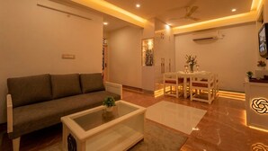A modern living room with a sofa, coffee table, and dining area. - The Collectors Loft-A Luxury Private Suit Near Jaipur City Center - Two-Bedroom Apartment (Jaipur)