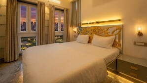A hotel room with a large bed, a city view through the window, an air conditioning unit, and a modern headboard. - The Collectors Loft-A Luxury Private Suit Near Jaipur City Center - Two-Bedroom Apartment (Jaipur)