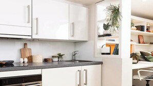 Una cocina moderna con armarios blancos, encimera negra y horno empotrado.
