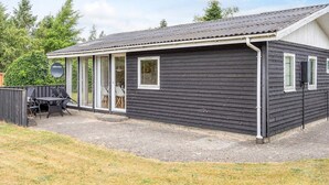 A single-story building with a dark exterior, large windows, and a covered patio area. - 4 Person Holiday Home in Hals (Hals)