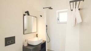A modern bathroom with a white sink, a large mirror, a handheld showerhead, and a towel rack. - Villa Paradiso 1 With Private Pool (Malevizi)