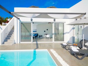 A modern pool area with a clear view of the interior, including a dining area and a staircase leading to the upper floors. - Villa Paradiso 1 With Private Pool (Malevizi)
