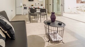 A modern kitchen with white cabinets, a dining area with a table and chairs, and a large sliding glass door leading to an outdoor patio. - Villa Paradiso 2 With Private Pool (Malevizi)
