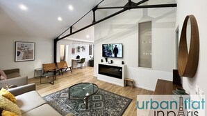 A modern living room with a glass coffee table, a sofa, a TV, and a fireplace.