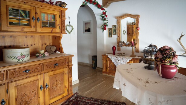 Ein traditioneller Holzkorpus mit Schubladen und ein Tisch mit weißer Spitzenleinentuch.