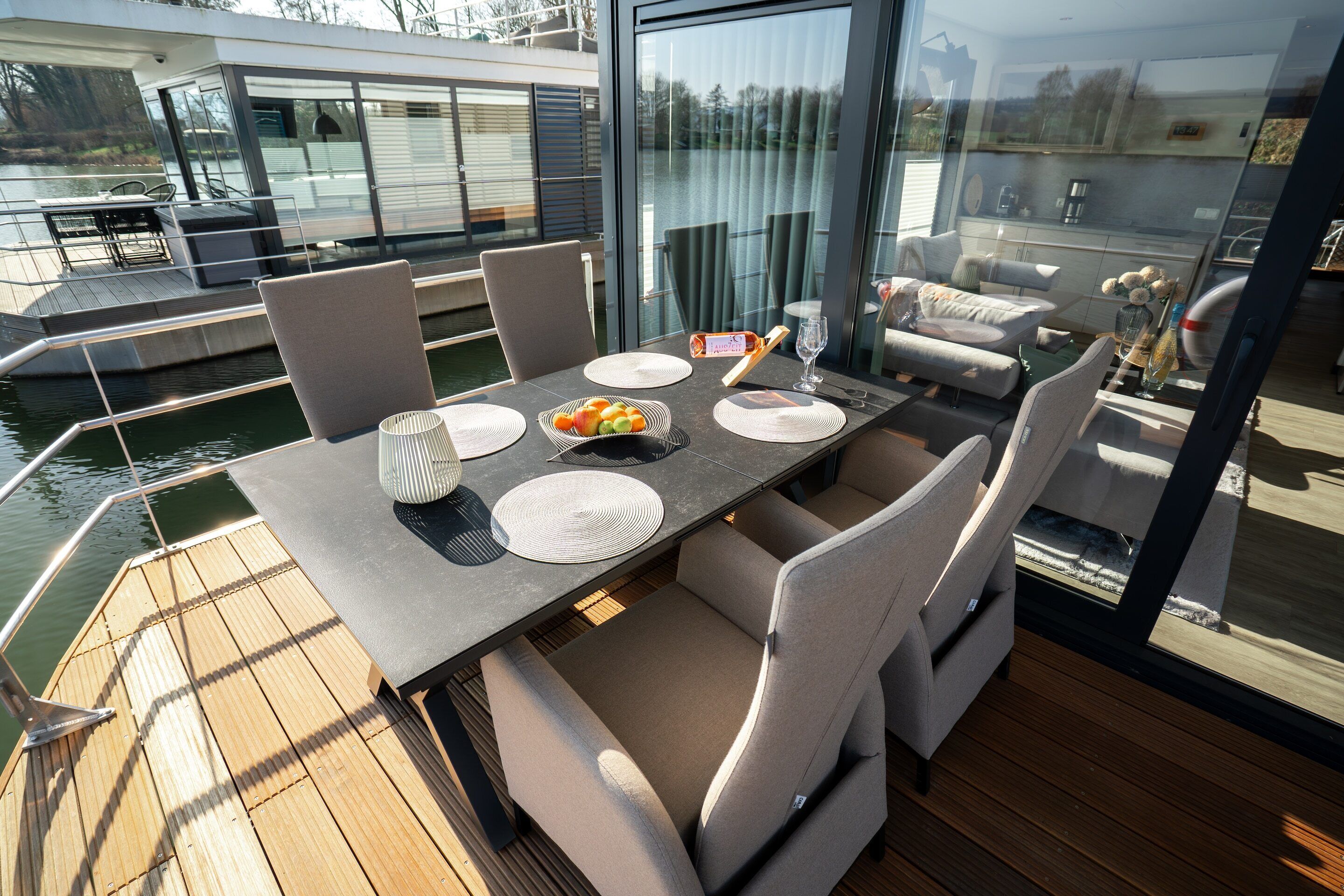 A dining area with a table set for four, surrounded by chairs, overlooking a body of water.