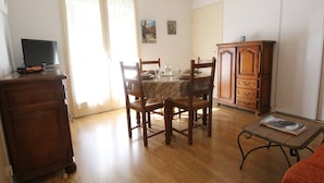 A dining area with a wooden table, chairs, and a cabinet. - T2 Luchon Center - Balcony - Parking Included - Pets Welcome (Bagnères-de-Luchon)