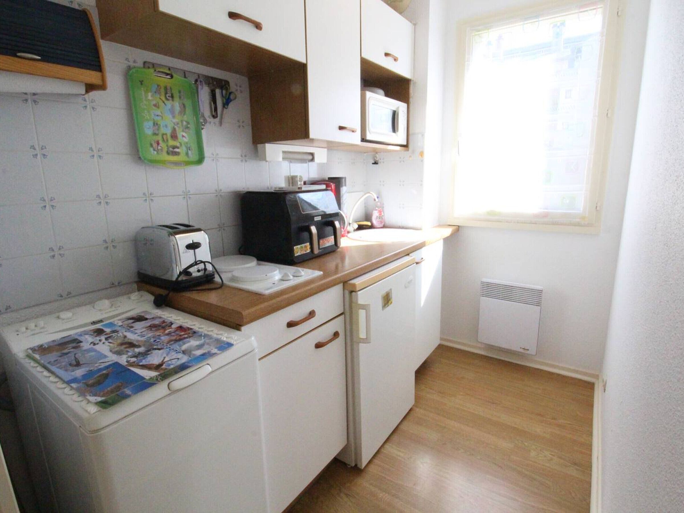 A compact kitchen with white cabinets, a microwave, a toaster, and a small sink.