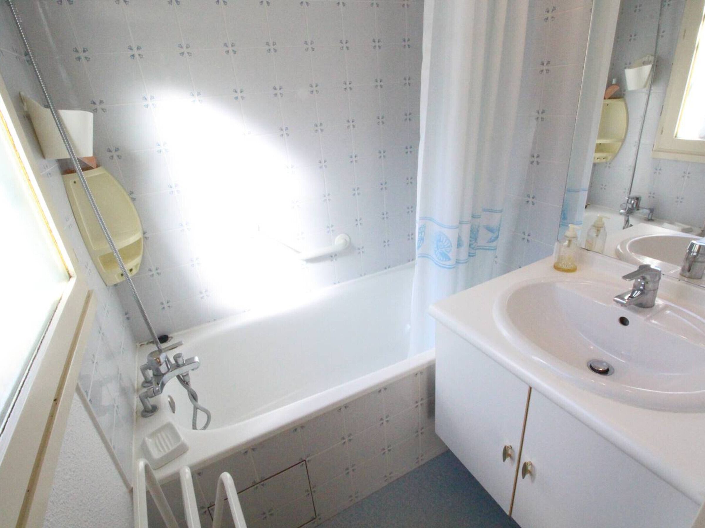 A bathroom with a bathtub, a sink, and a mirror.