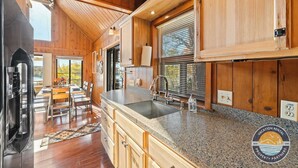 Une cuisine spacieuse avec des meubles en bois, un plan de travail en granit et une grande fenêtre équipée de stores.