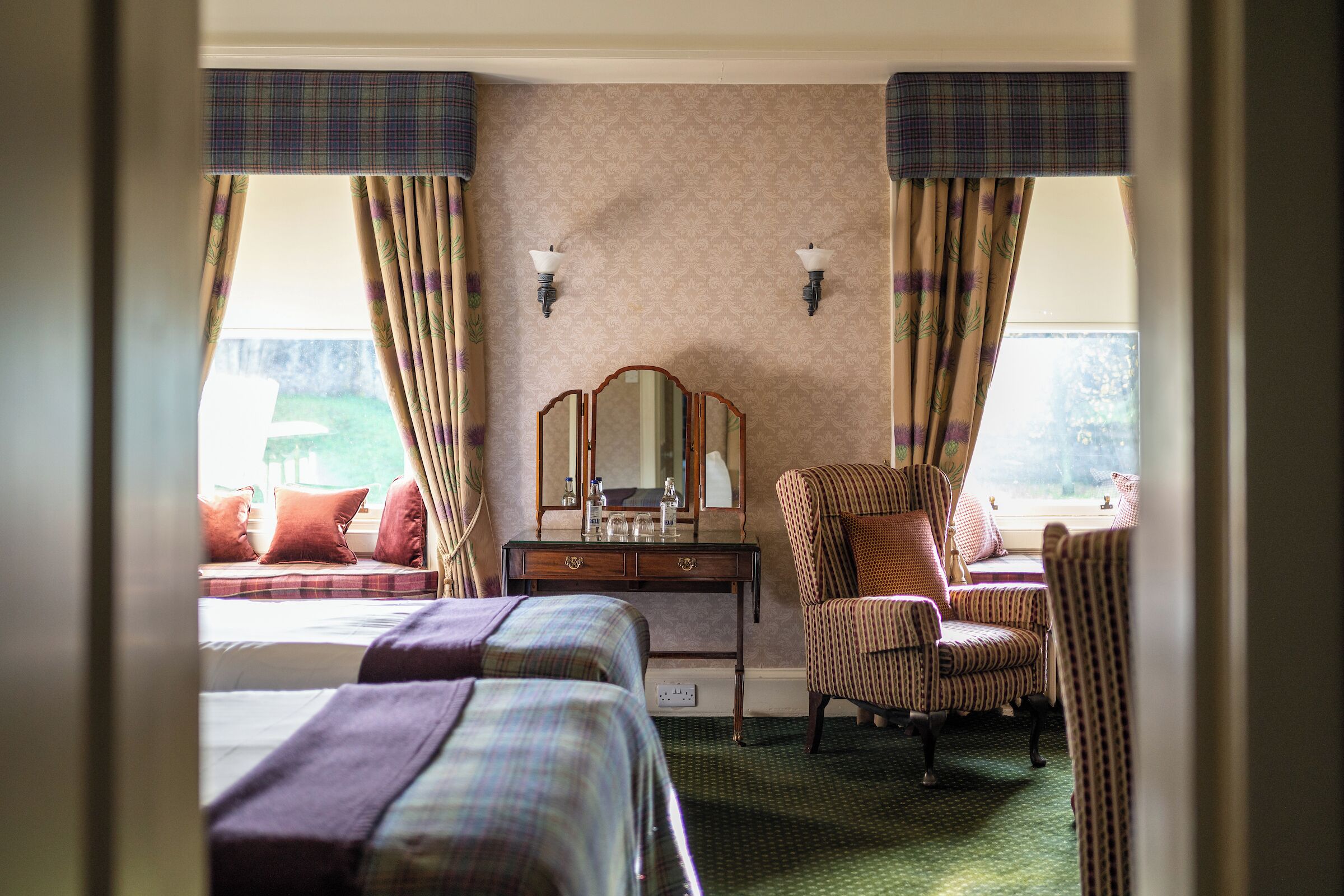 Une chambre d’hôtel avec deux lits, une chaise, une commode et un miroir.