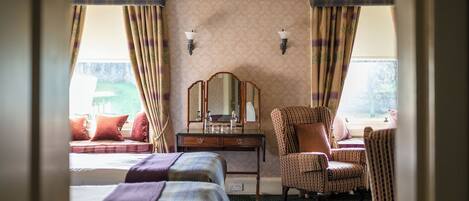 Une chambre d’hôtel avec deux lits, une chaise, une commode et un miroir.