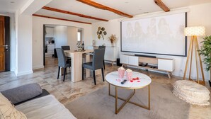 A modern living room with a dining area, wooden beams, a TV, popcorn, and a projector screen. - Piscine-Jacuzzi-Videoprojector-Clim La Perle Rare (Mougins)