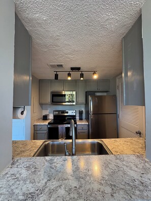 A kitchen with granite countertops, stainless steel appliances, and a built-in microwave.