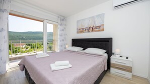 Un dormitorio con una cama grande, una mesita de noche, un cuadro y vistas a un paisaje.