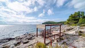 Eine felsige Küstenlandschaft mit einem Holzbau, möglicherweise eine Strandhütte, mit Blick auf das Meer.