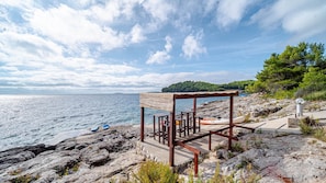 A rocky coastal area with a wooden structure, possibly a beach hut, overlooking the sea. - Villa Green by Villas Guide (Blato)