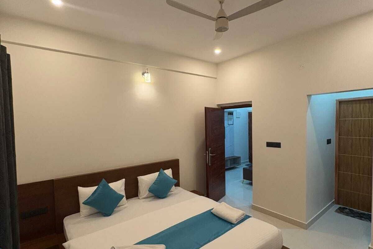 A hotel room with a large bed, a ceiling fan, and a view of the hallway.
