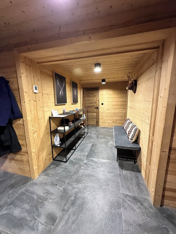 Un intérieur en bois avec un banc, des étagères et une porte.