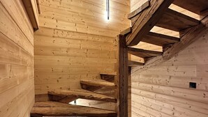 A wooden staircase with a modern light fixture and a sloped ceiling. - CHALET LE CAIRN view of the village Large open spaces 5 minutes from the cable car (Valloire)