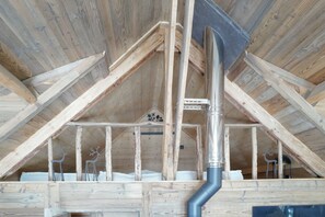 A wooden attic room with a sloped ceiling, exposed beams, and a central ventilation duct. - CHALET LE CAIRN view of the village Large open spaces 5 minutes from the cable car (Valloire)