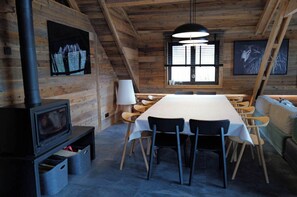 A cozy cabin with a long dining table, wooden walls, a fireplace, and a large window. - CHALET LE CAIRN view of the village Large open spaces 5 minutes from the cable car (Valloire)