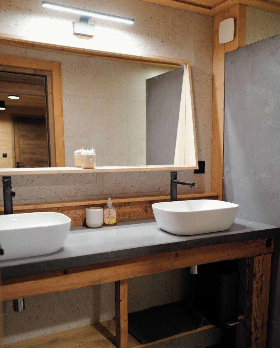 A bathroom with two sinks, a large mirror, and a wooden vanity.