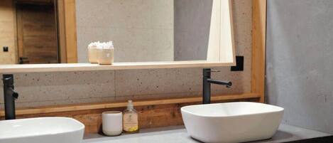 A bathroom with two sinks, a large mirror, and a wooden vanity.