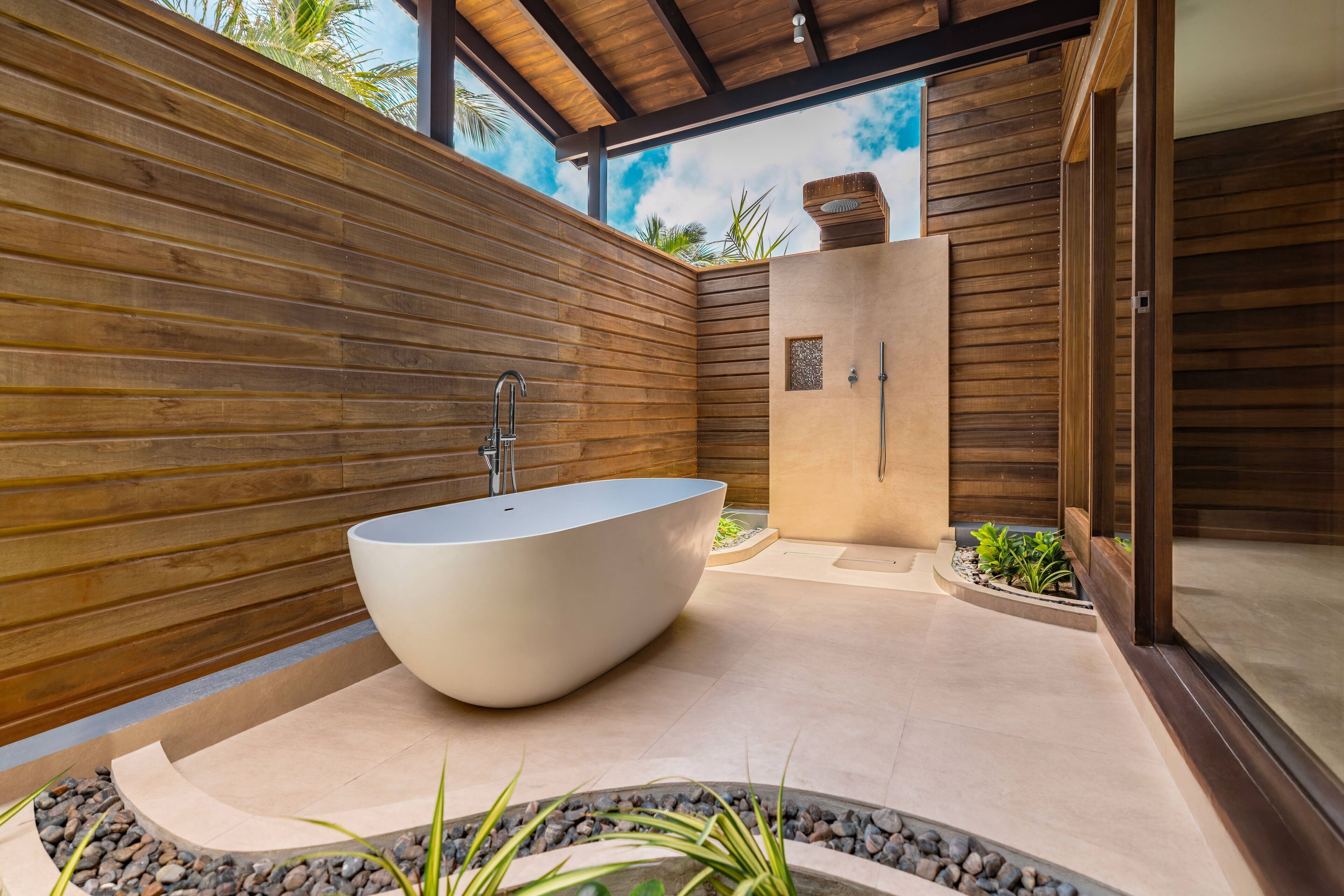 A modern bathroom with a freestanding bathtub, a shower area, and a wooden wall.