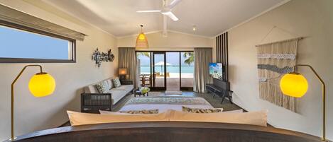 A bedroom with a large bed, a ceiling fan, and a view of the beach.