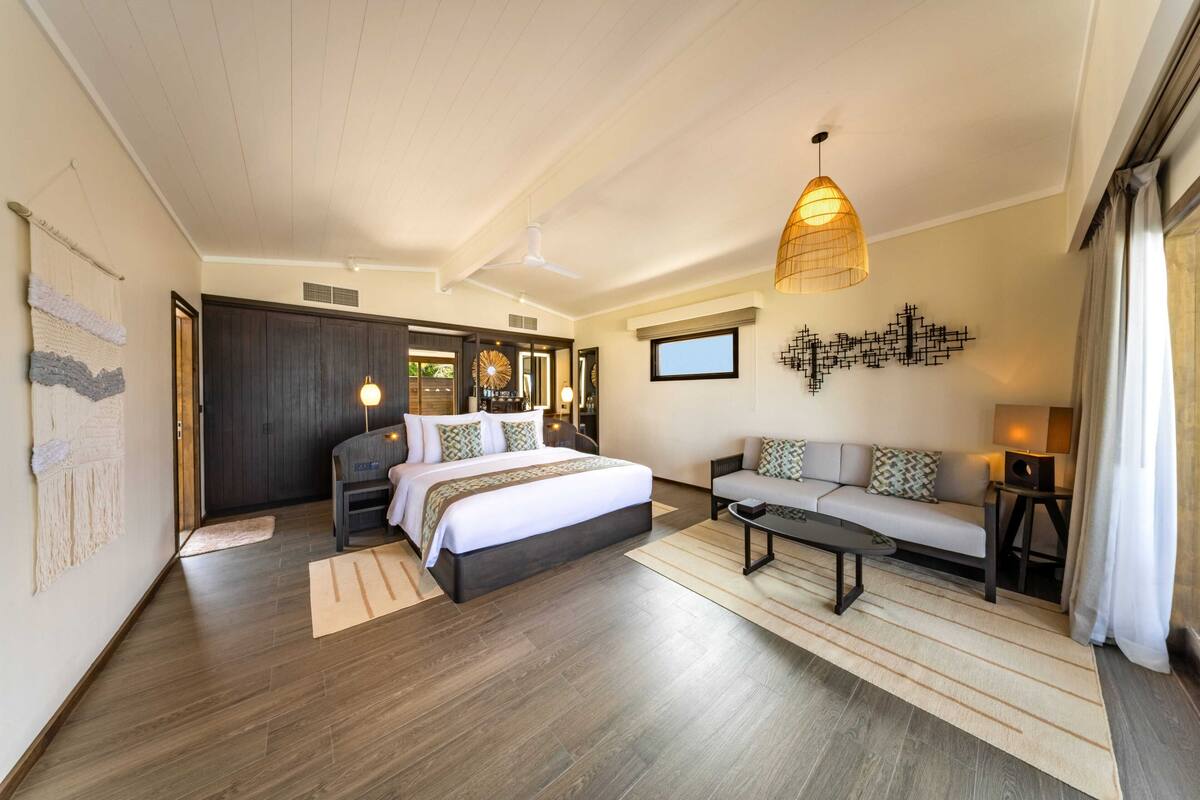 Een moderne hotelkamer met een groot bed, een slaapbank, een bijzettafeltje en een hanglamp.